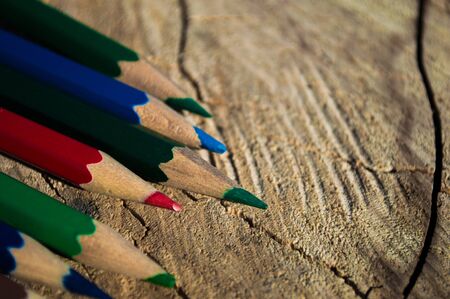 Pencils of different colors on a stump. Pencils closeup with bokeh. Photo with copyspace like postcardの写真素材