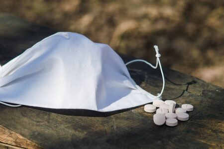 White  pills lie on an old bench. Pills or tablets closeup with bokeh. Concept photo on theme Coronavirus and Covid-19.の写真素材