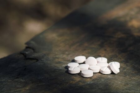 White  pills lie on an old bench. Pills or tablets closeup with bokeh.