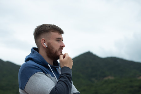 Portrait of bearded handsome pensive thoughtful guy, listen music in earphones, young upset sad...