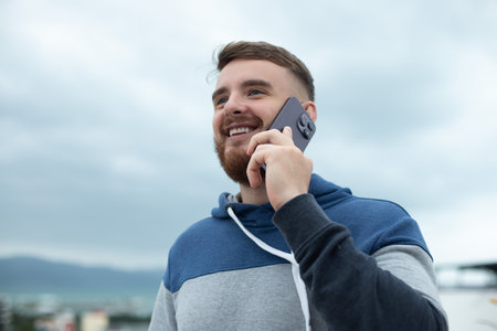 happy young man talking on the mobile on the street, guy making a phone call, feeling happy and...