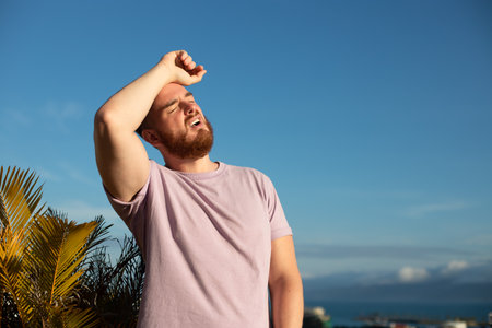portrait of tired sick exhausted man, handsome guy is suffering from hot Summer heat stroke,...