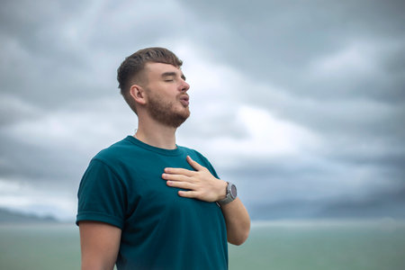 happy handsome free guy, young calm relaxed carefree man traveler with open raised hands enjoy sea, ocean view, person feeling good, breath deep deeply fresh air. Freedom, travel, happiness conceptの写真素材
