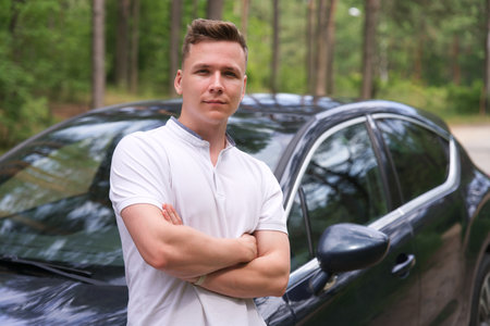 portrait of happy young handsome man, positive guy standing near his car smiling, looking at camera,...
