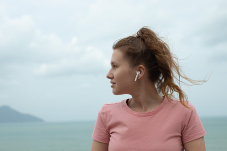 portrait of a beautiful girl in earphones on the natural background of ocean or sea in the mountain,...