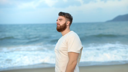 happy handsome free guy, young calm relaxed carefree man traveler enjoy sea on beach, ocean view, person feeling good, breath deep deeply fresh air. Freedom, travel, happiness concept, summer vacationの写真素材