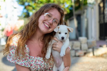 Young girl picked up a homeless dog and holding in his armson the street, a persons hand strokes the dog, abandoned, frightened homeless puppy in a shelter for dogsの写真素材