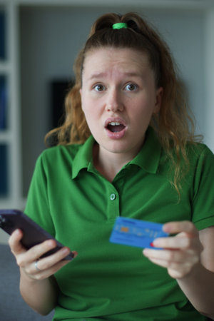 Internet fraud. Nervous sad upset unhappy confused young woman, stressed worried lady having problem with paying, buying online, shopping, stolen money, payments with credit blocked bank cardの写真素材