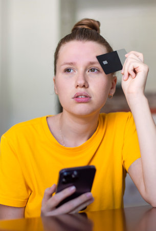 Portrait of happy girl, young positive pretty woman paying, holding credit bank card with phone,...