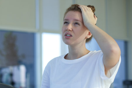 Tired exhausted young woman is training workout, running on treadmill in gym holding her head with...