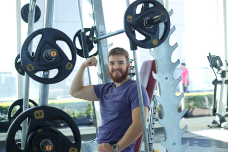Young happy athletic man is training in the gym doing exercise with barbell