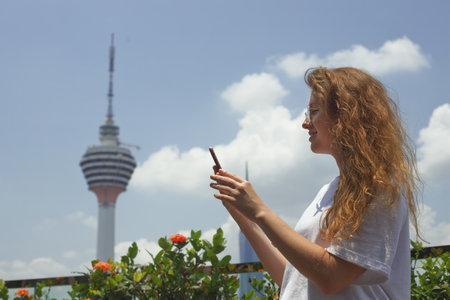 Young happy woman use cell mobile phone, looking at screen of smartphone outdoors with city metropolis view and smileの写真素材