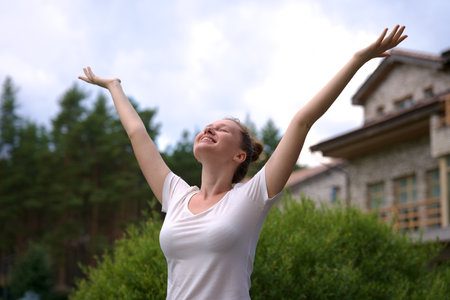 Portrait of happy young woman standing in the garden outside her luxury home and smiling and relax outsideの写真素材