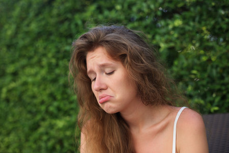 Portrait of sad upset frustrated young woman on natural green backgroundの写真素材