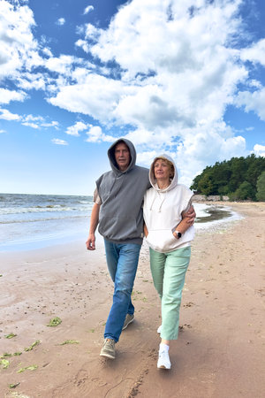 Portrait of happy elderly senior couple in love walking on a beach at summer, smile, laugh, have funの写真素材