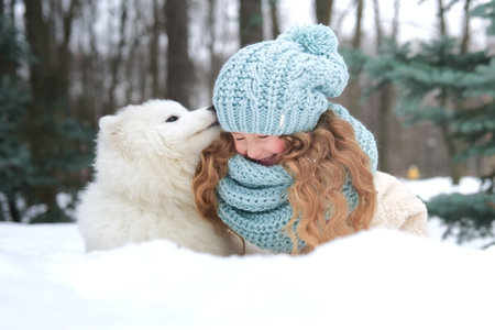 Little beautiful girl, cute happy positive child kid is lying on snow, play, having fun with her big white dog at winter day in park or forestの写真素材