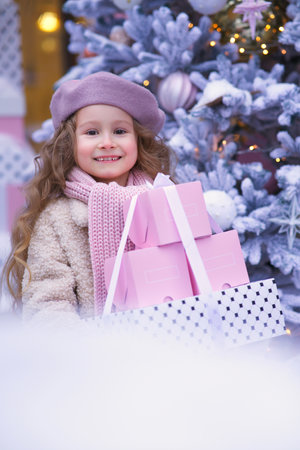 Portrait of young beautiful kid, child girl in Christmas decoration at winter snowy day near Christmas treeの写真素材