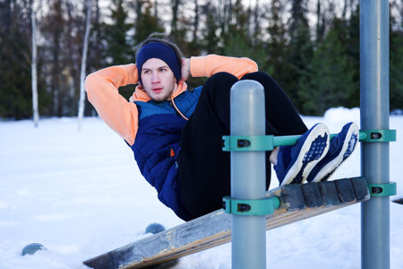 Young fit man is training workout outdoors at winter cold snowy day. Healthy fitness lifestyle...