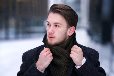Portrait of young handsome man in classic coat at winter cold day outdoorsの写真素材