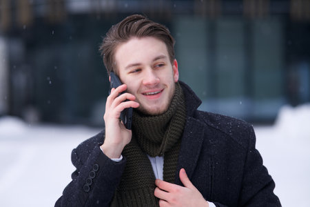 Portrait of happy businessman talk on cell mobile phone at winter cold snowy day outdoorsの写真素材