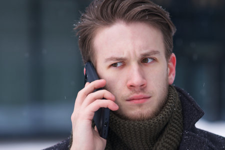 Sad upset man talk on cell mobile phone at winter cold snowy dayの写真素材