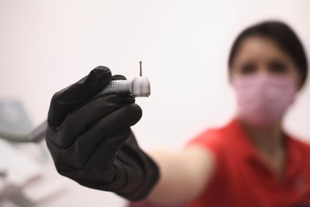 Woman dentis hold in hand dental device for drilling teeth. Drill machine