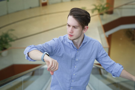 Young man, student or office worker in shirt looking at his wrist watches and hurry up, check timeの写真素材
