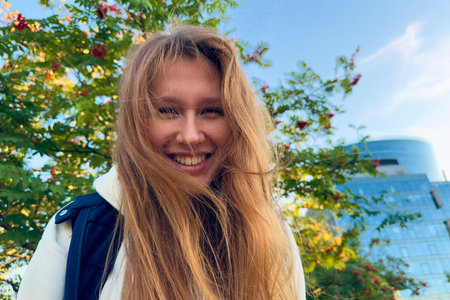 Portrait of happy cheerful young beautiful woman walking outdoors at summer or golden autumn park,...