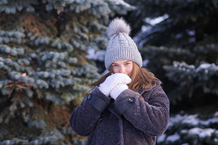 Portrait of beautiful girl young frozen pretty woman standing walking in winter snowy park at cold...