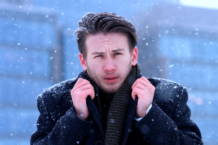 Young man, businessman shiver tremble in coat at winter cold snowy weather outdoorsの写真素材