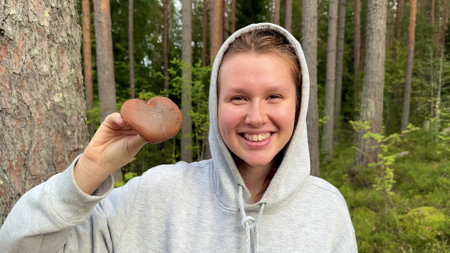 happy young woman in the forest with a mushroom, forester, autumnの写真素材