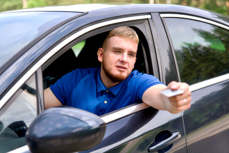 Young man driver pay with credit bank card from his carの写真素材
