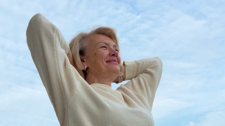 adult elderly happy woman on the balcony against the skyの写真素材