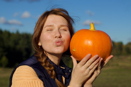 Happy young woman in nature, countryside with pumpkin, concept autumn, harvest, village, halloweenの写真素材