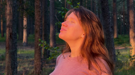 Happy young woman enjoying nature at summer pine forest, breathing deep fresh airの写真素材