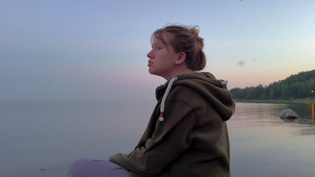 Young depressed sad woman sitting on the beach in the evening
