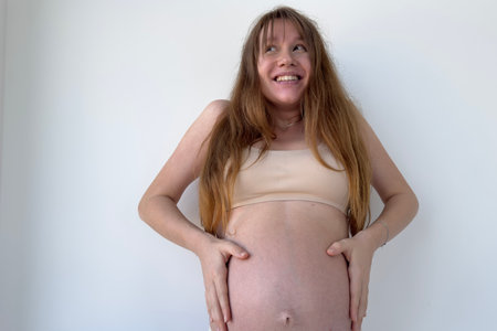 Happy pregnant young woman on white background in lingerie