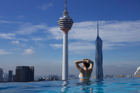 Young woman in a roof top swimming pool with beautiful city view. Vacation in Kuala lumpur, Malaysia