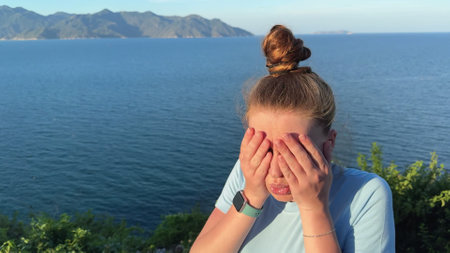 young woman afraid of heights, looking down in mountainsの写真素材