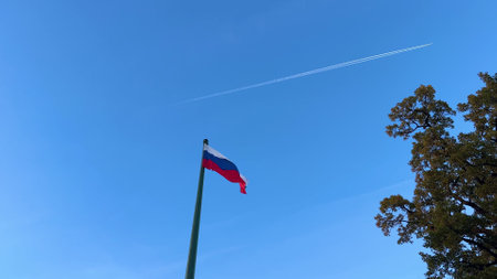 Russian flag against the sky and a plane taking off or a rocket in the skyの写真素材