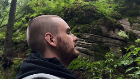 young man standing in dark forest near mountain and enjoying fresh air. autumn, walk, natureの写真素材