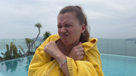 young woman by the pool against the backdrop of the sea. summer, vacation, and cold weather