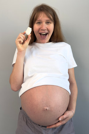 beautiful pregnant woman holding piece of chalk, biting. concept eat chalk, health, calciumの写真素材