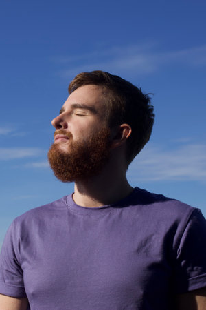 handsome young man against blue sky vertical photo breathe fresh air, relax, in the sunの写真素材