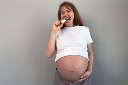 beautiful pregnant woman holding piece of chalk, biting. concept eat chalk, health, calciumの写真素材