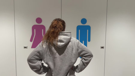 Unhappy sad upset young man with fat on his stomach, worried about body fat touching belly standing at home near closetの写真素材