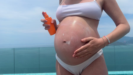 beautiful pregnant young girl with big belly uses cga cream in summer before tanningの写真素材