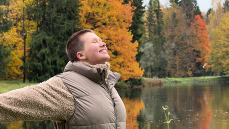 Happy young woman enjoying autumn weather and walking in the parkの写真素材