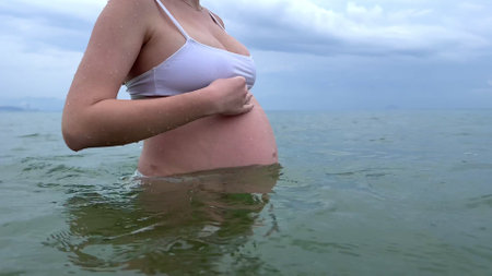 Happy pregnant young woman enjoy summer vacation on the beach, sea in tropical country, swimmingの写真素材