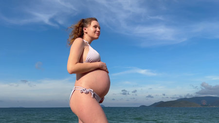 Happy pregnant young woman enjoy summer vacation on the beach, sea in tropical country, swimmingの写真素材